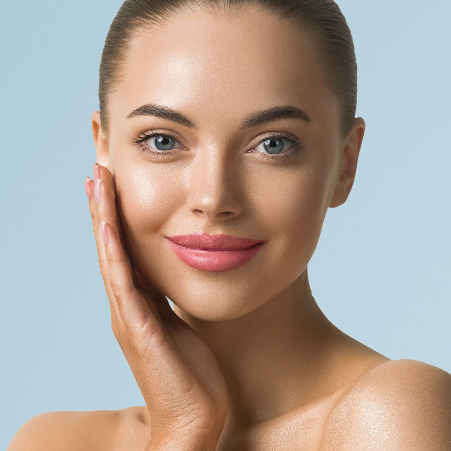 Clean skin woman face close up beauty tanned face beautiful smile. Blue background. Touching face.